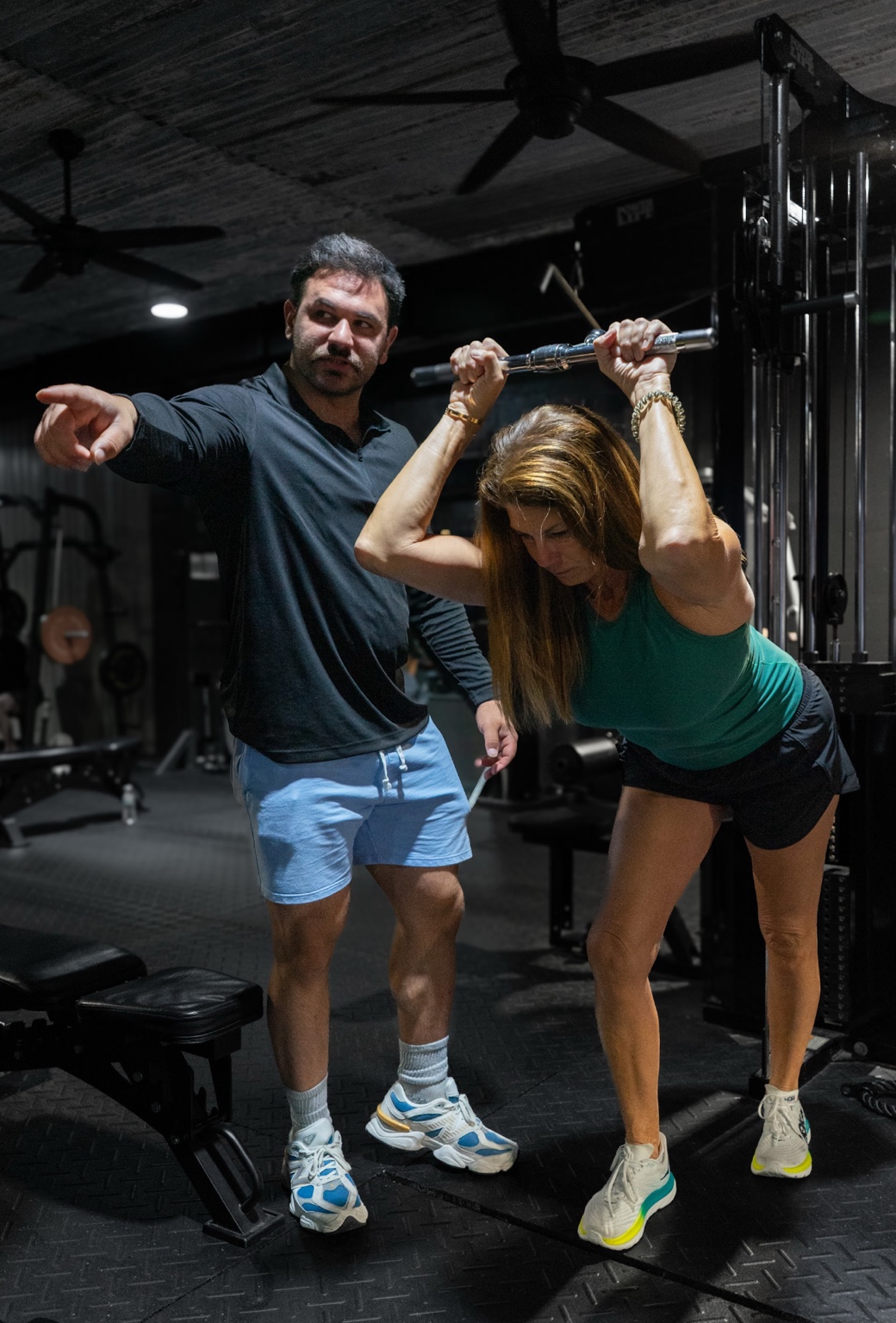 Trainer coaching a client on cable equipment